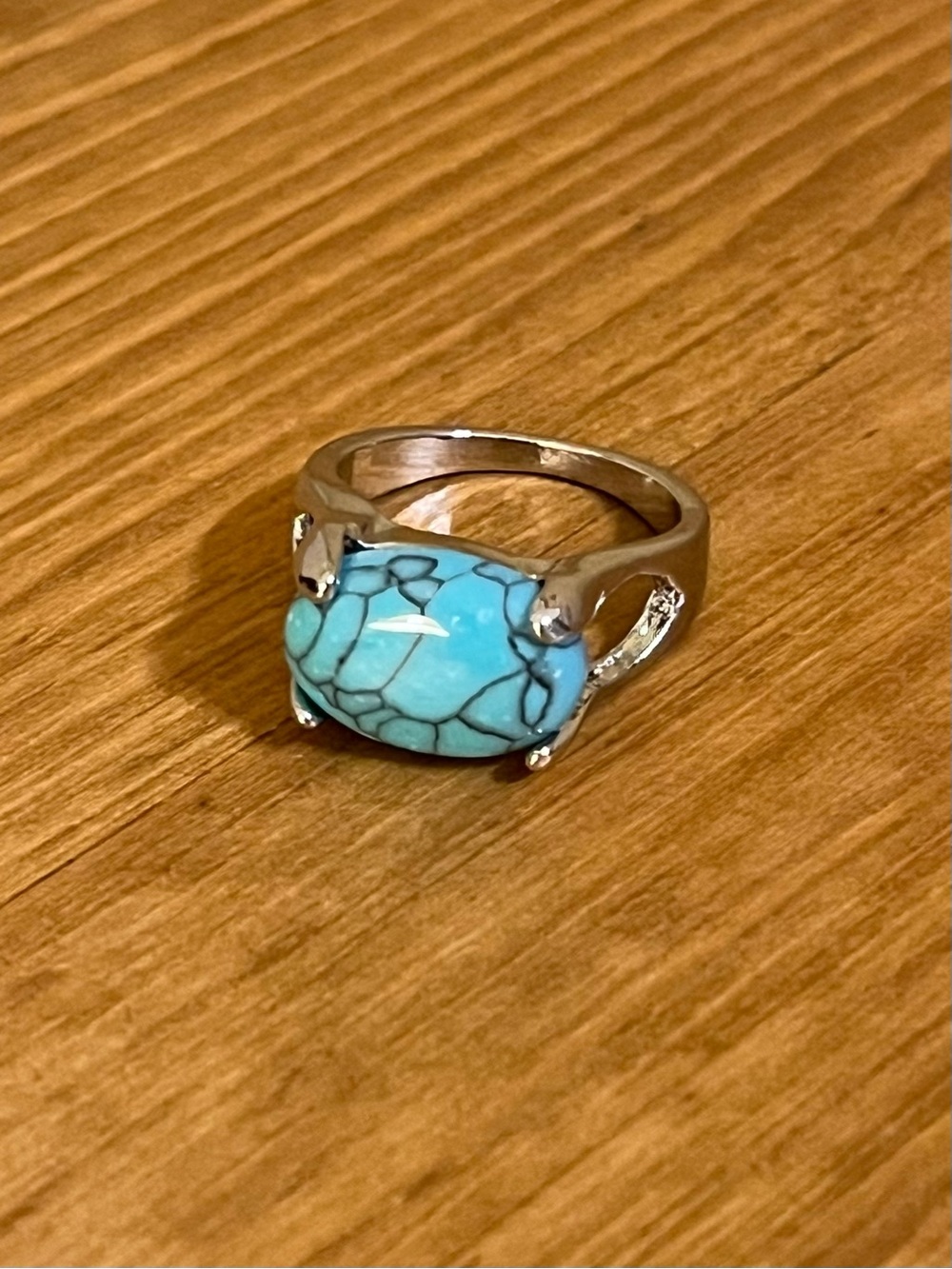 Turquoise like ring set horizontally with prongs on a silver tone band size 6